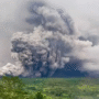 “Pemandangan Gunung Semeru dengan kepulan asap vulkanik yang membumbung tinggi, menunjukkan aktivitas guguran dan erupsi.”